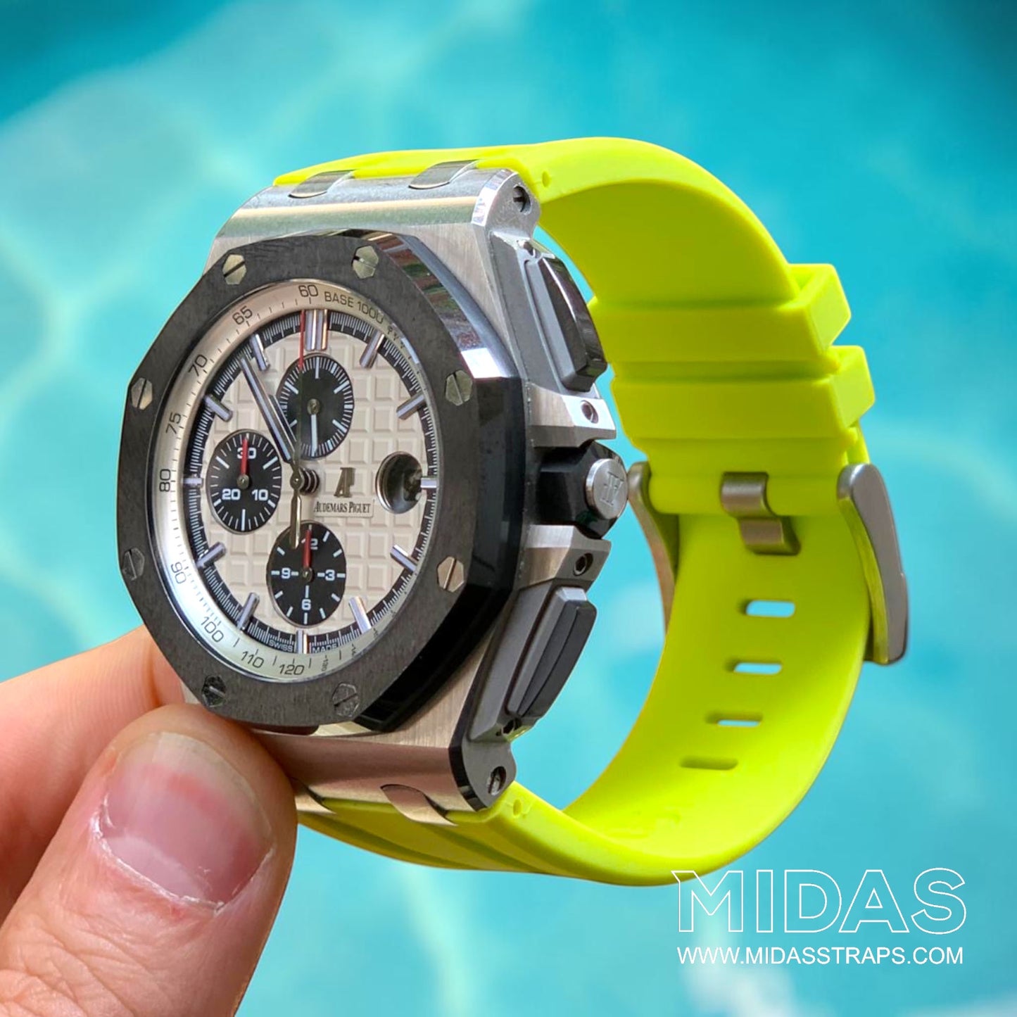 Hand-held Audemars Piguet Royal Oak Offshore 44mm fitted with an acid lime green replacement rubber strap in a poolside lifestyle photograph.