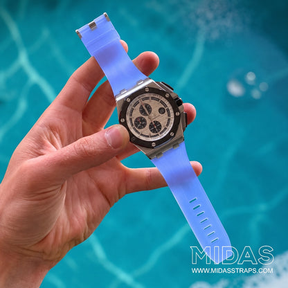 Hand-held Audemars Piguet Royal Oak Offshore 44mm watch fitted with a transparent ice blue replacement rubber strap by MIDAS Straps against a poolside background.