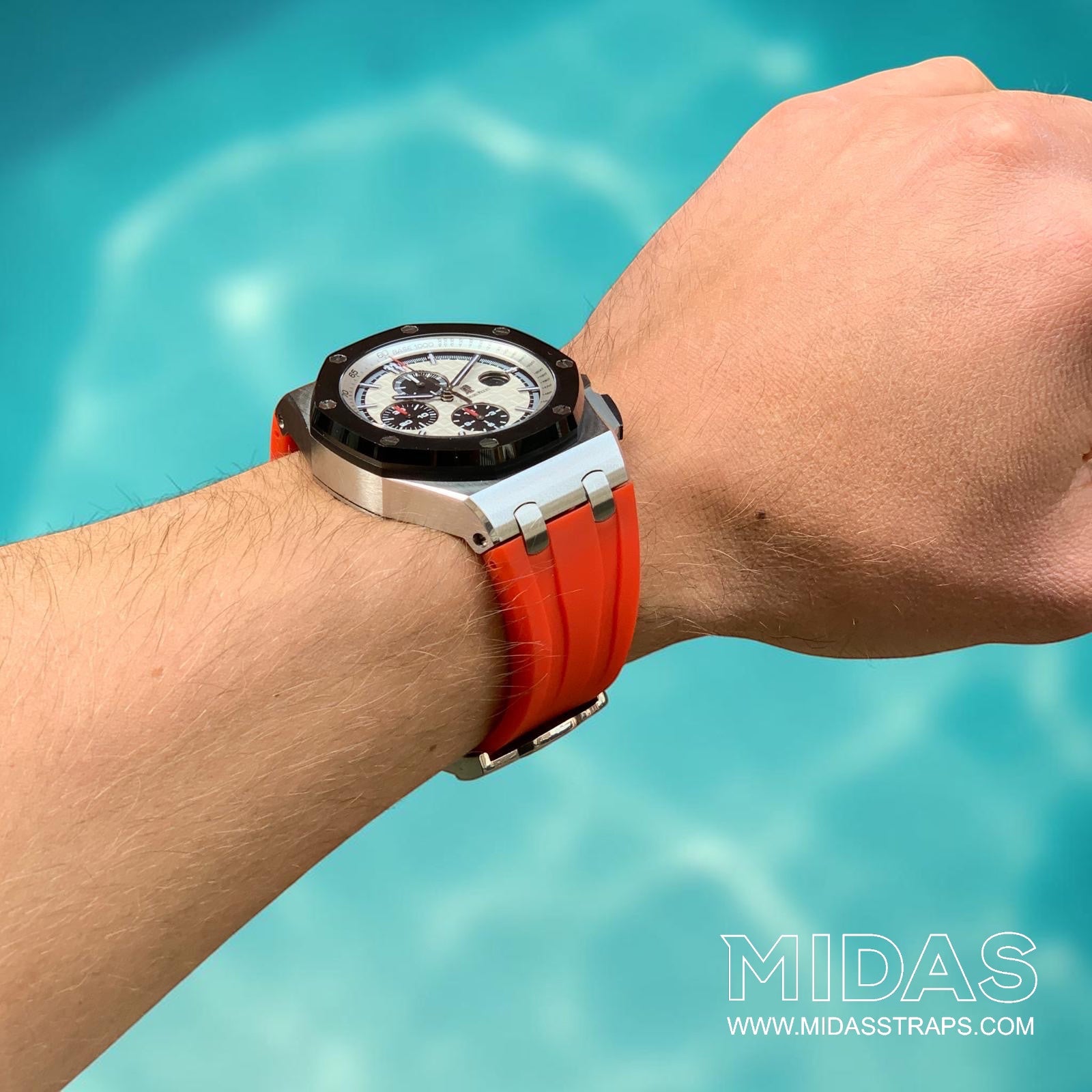 Long-distance wrist view of an Audemars Piguet Royal Oak Offshore 44mm with a red replacement rubber strap in an outdoor poolside setting.