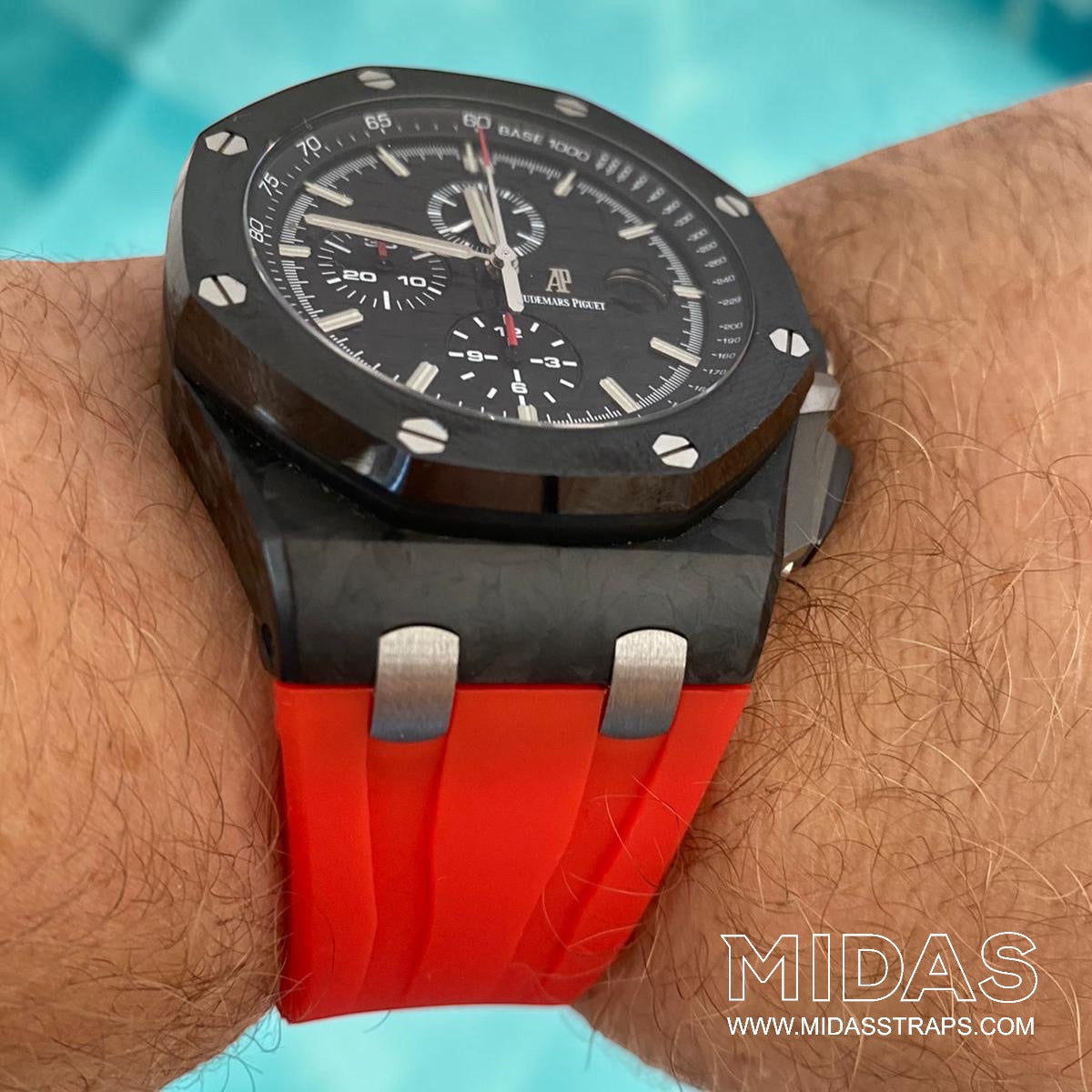Audemars Piguet Royal Oak Offshore 44mm fitted with a red replacement rubber strap on wrist beside a swimming pool.