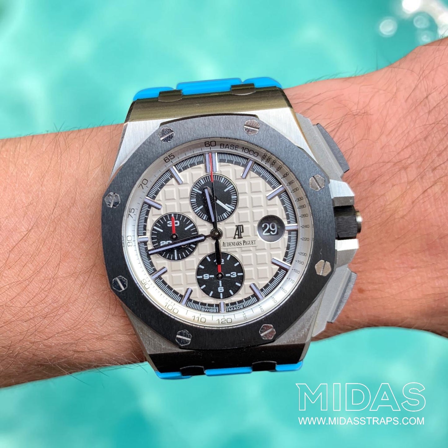 Audemars Piguet Royal Oak Offshore 44mm fitted with a light blue replacement rubber strap in a poolside lifestyle photograph.