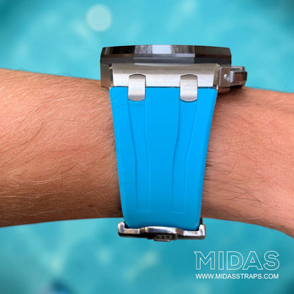 Front view of a light blue replacement rubber strap fitted to an Audemars Piguet Royal Oak Offshore 44mm watch on wrist beside a swimming pool.