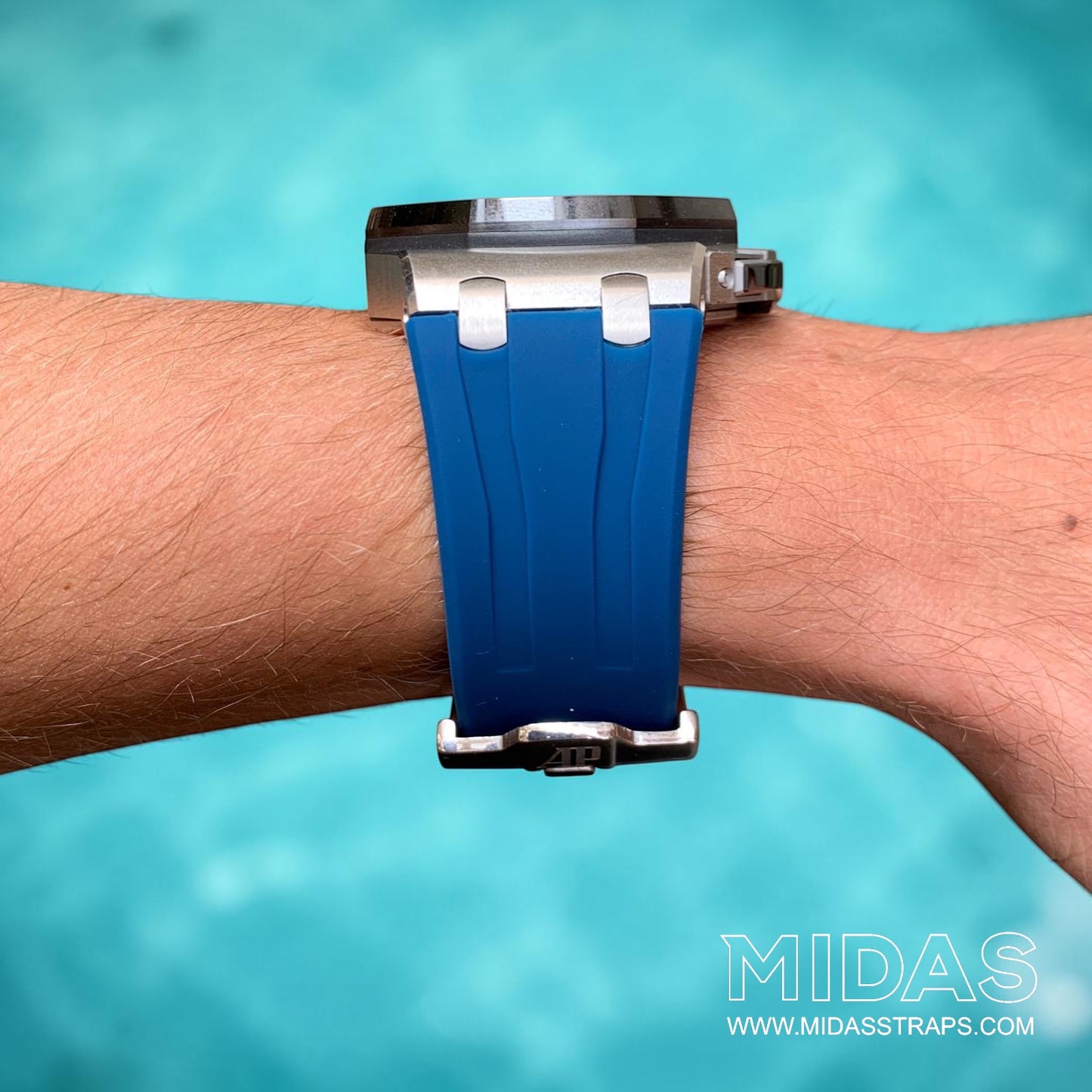 Front view of a royal navy blue replacement rubber strap fitted to an Audemars Piguet Royal Oak Offshore 44mm watch on wrist beside a swimming pool.