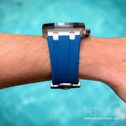 Front view of a royal navy blue replacement rubber strap fitted to an Audemars Piguet Royal Oak Offshore 44mm watch on wrist beside a swimming pool.