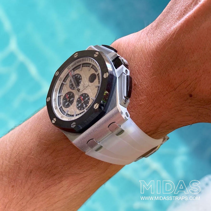 Angled wrist view of an Audemars Piguet Royal Oak Offshore 44mm with a transparent clear replacement rubber strap beside a swimming pool.