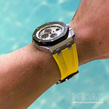 Yellow replacement rubber strap fitted to an Audemars Piguet Royal Oak Offshore 44mm watch on wrist in an outdoor poolside setting.